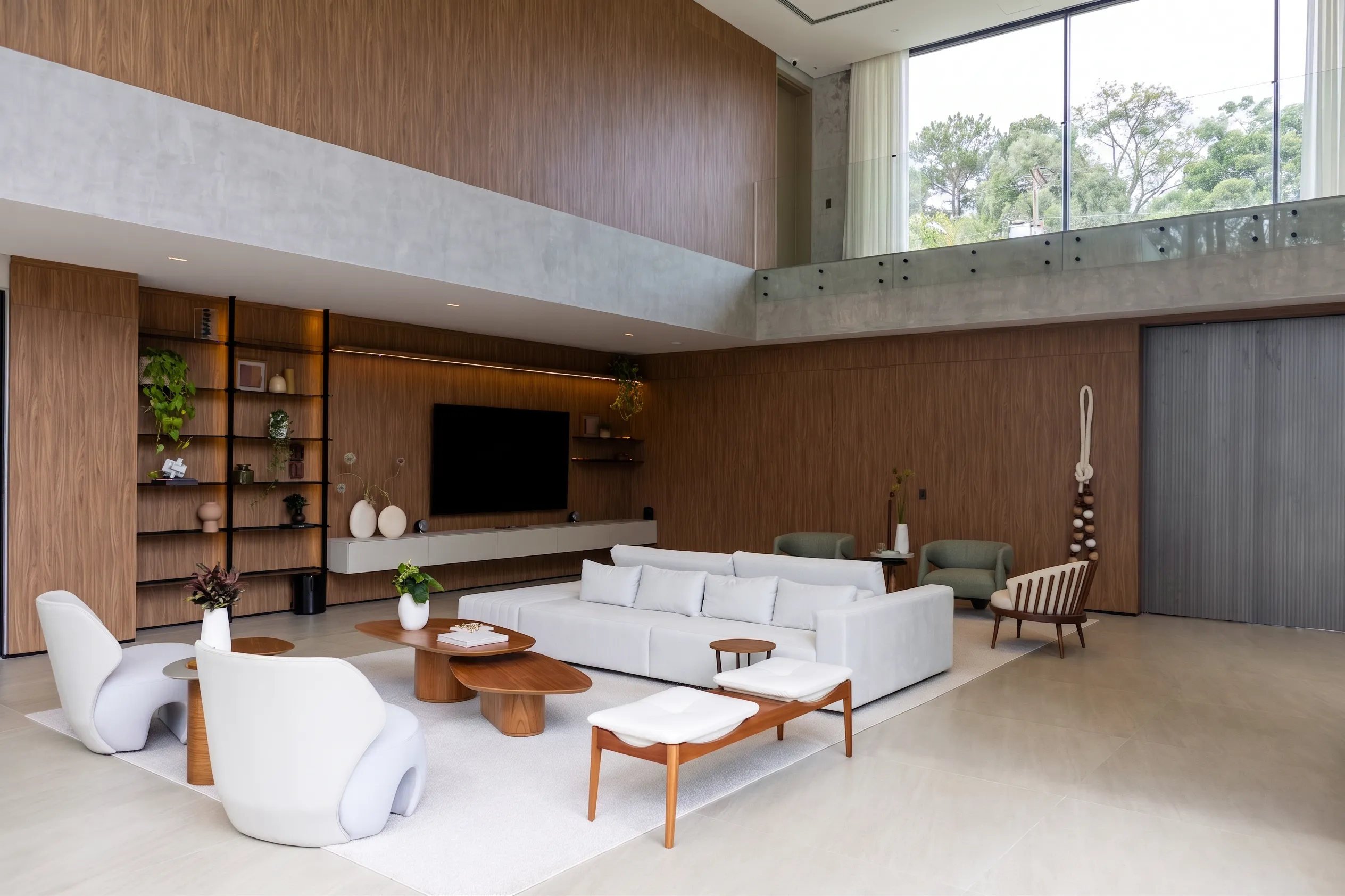 Estar da Casa Entreverdes com painel de TV em madeira, sofá modular, poltronas verdes, mesas orgânicas e luz indireta