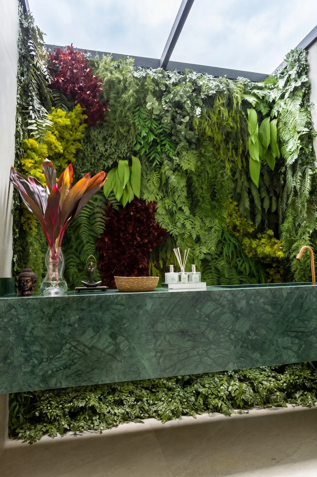 Lavabo da Casa Entreverdes com jardim vertical, bancada em mármore verde, cuba esculpida e iluminação zenital