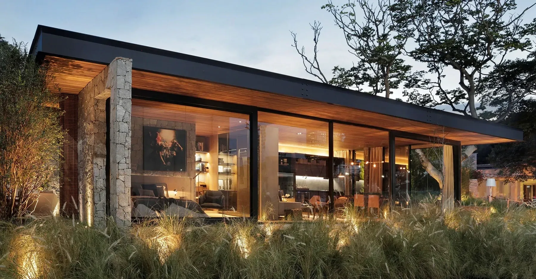 Fachada horizontal de residência contemporânea com estrutura metálica, paisagismo e espelho d’água.