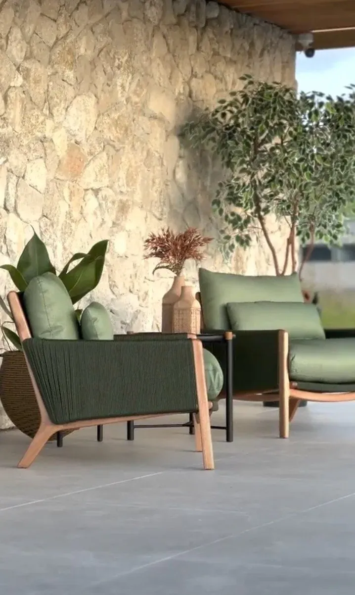 Lounge externo da Morada Pôr do Sol com pedra natural, mobiliário verde e paisagismo