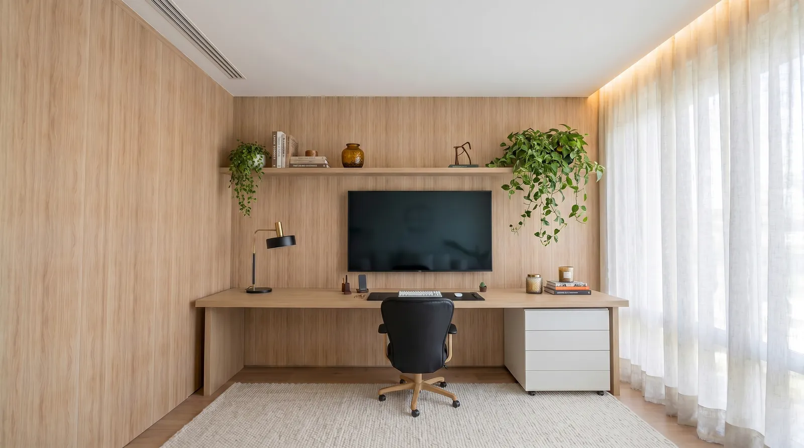 Escritório da Casa Trama em Alphaville Campinas com marcenaria em madeira clara, bancada de trabalho, cortina de linho, plantas e iluminação suave