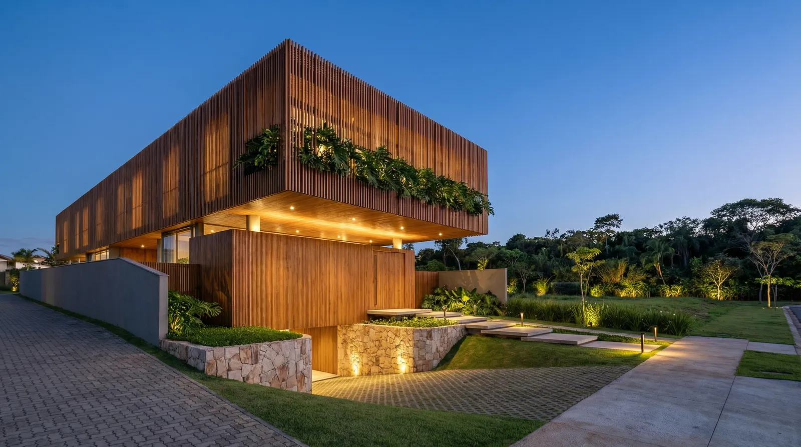 Volume superior da Casa Trama envolvido por brise de alumínio com pintura, com balanço sobre a base térrea, jardim tropical e iluminação cênica